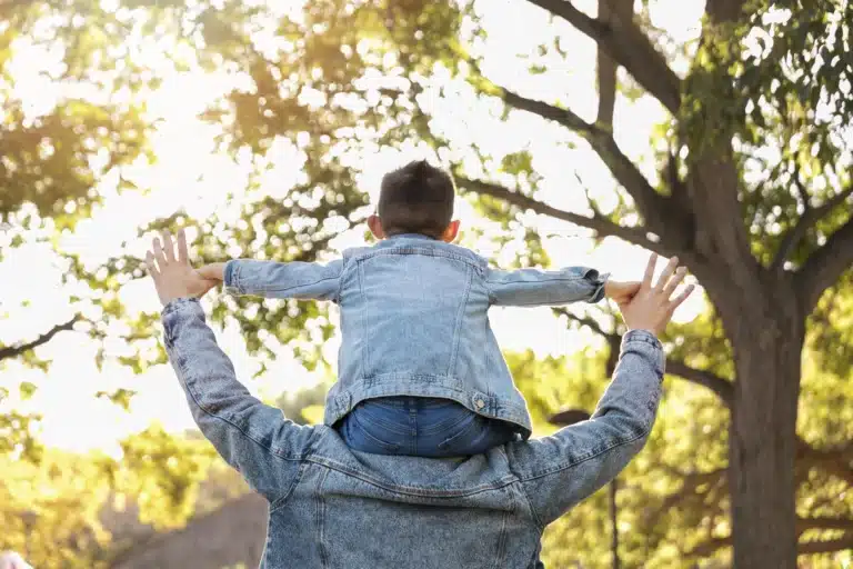 medium shot man holding kid shoulders - ¿Qué es la artrodesis vertebral? Todo lo que necesitas saber